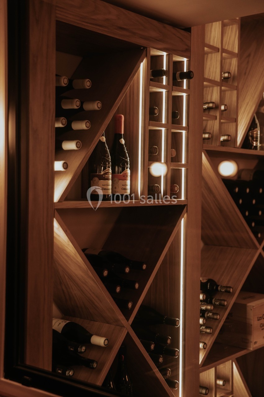 Cave à vin en bois avec bouteilles disposées sur des étagères éclairées par une lumière chaude.