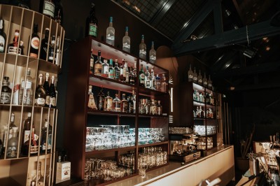 Terrasse extérieure avec tables et chaises noires, entourée de végétation et de bâtiments résidentiels.