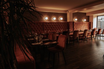 Terrasse extérieure avec tables et chaises noires, entourée de végétation et de bâtiments résidentiels.