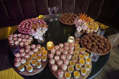 Table garnie de desserts variés, incluant une pièce montée, des verrines et des pâtisseries, dans un cadre tamisé.