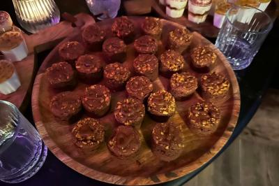 Table garnie de desserts variés, incluant une pièce montée, des verrines et des pâtisseries, dans un cadre tamisé.