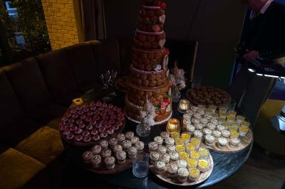 Table garnie de desserts variés, incluant une pièce montée, des verrines et des pâtisseries, dans un cadre tamisé.