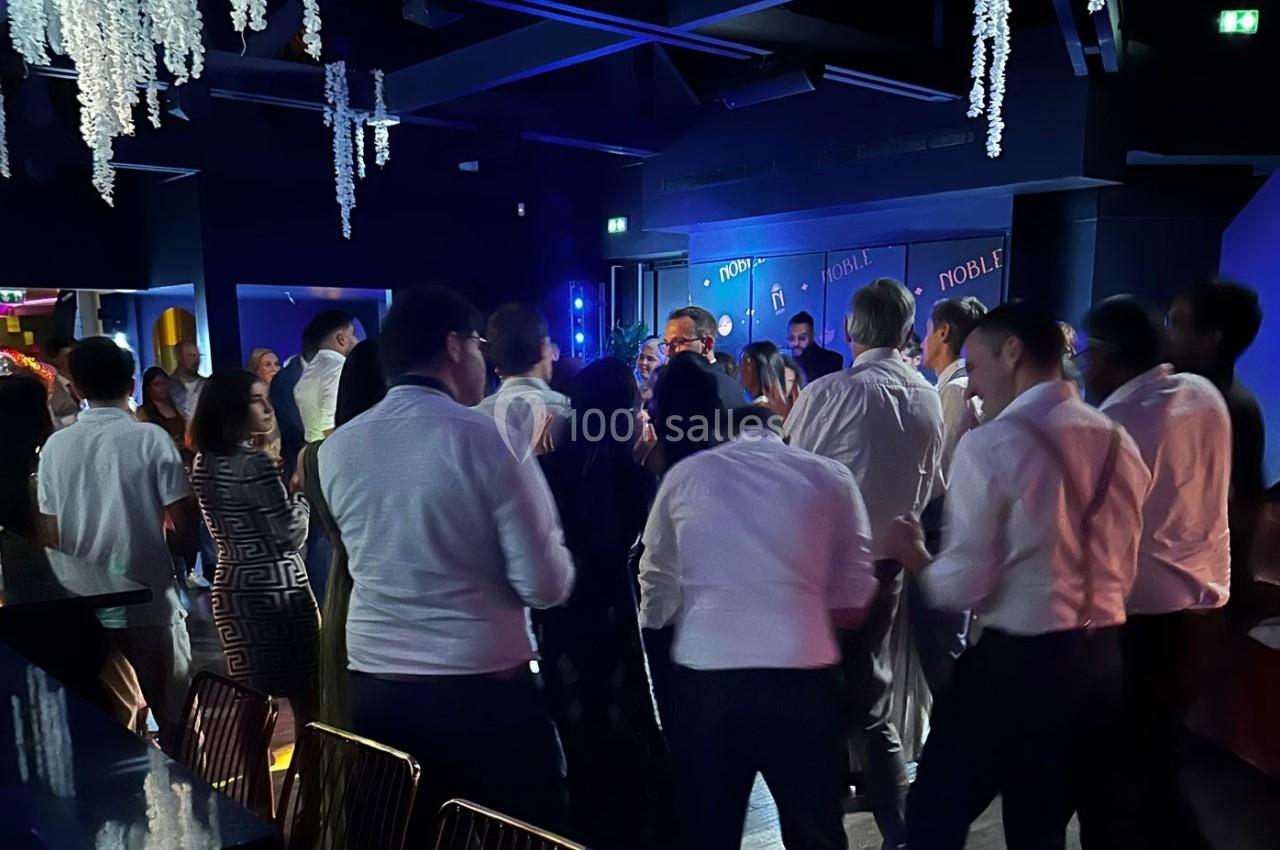 Groupe de personnes debout dans une salle sombre, éclairée par des lumières colorées, lors d'un événement festif.