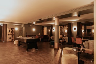 Salle de restaurant chaleureuse avec banquettes en velours rouge, chaises en bois et éclairage tamisé.