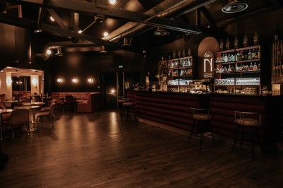 Salle de restaurant chaleureuse avec banquettes en velours rouge, chaises en bois et éclairage tamisé.