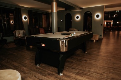 Salle de restaurant chaleureuse avec banquettes en velours rouge, chaises en bois et éclairage tamisé.