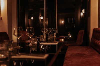 Salle de restaurant chaleureuse avec banquettes en velours rouge, chaises en bois et éclairage tamisé.