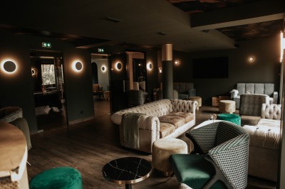 Salle de restaurant chaleureuse avec banquettes en velours rouge, chaises en bois et éclairage tamisé.