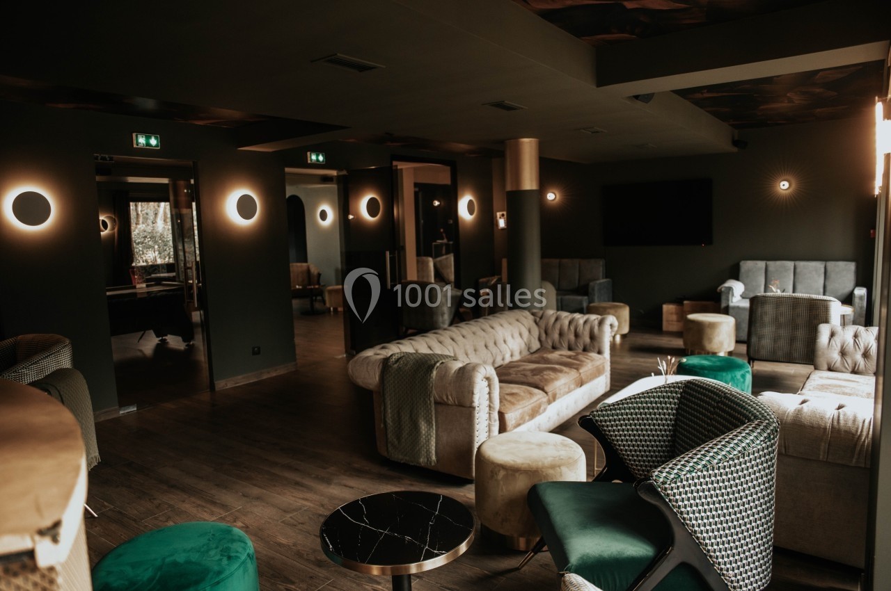 Salon moderne avec canapés et fauteuils élégants, éclairé par des appliques murales rondes dans une ambiance tamisée.