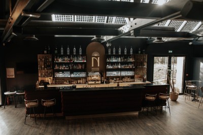 Salle de restaurant chaleureuse avec banquettes en velours rouge, chaises en bois et éclairage tamisé.