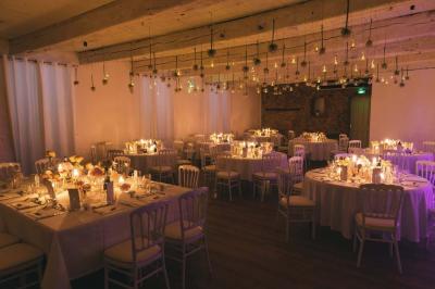 Cour intérieure pavée entourée de murs en pierre, avec des plantes grimpantes et des fenêtres sur une façade.