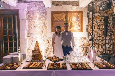 Cour intérieure pavée entourée de murs en pierre, avec des plantes grimpantes et des fenêtres sur une façade.