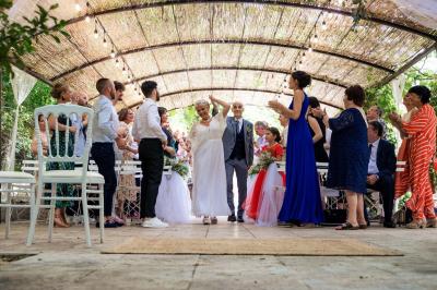 Cour intérieure pavée entourée de murs en pierre, avec des plantes grimpantes et des fenêtres sur une façade.