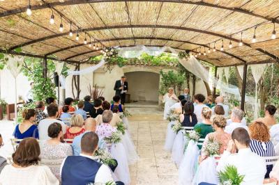 Cour intérieure pavée entourée de murs en pierre, avec des plantes grimpantes et des fenêtres sur une façade.