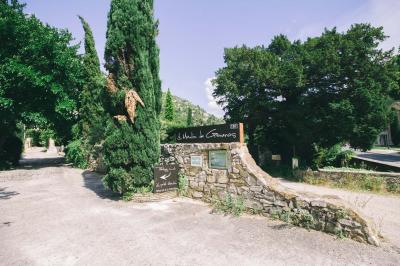 Cour intérieure pavée entourée de murs en pierre, avec des plantes grimpantes et des fenêtres sur une façade.