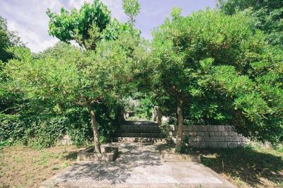 Cour intérieure pavée entourée de murs en pierre, avec des plantes grimpantes et des fenêtres sur une façade.