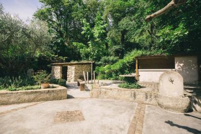Cour intérieure pavée entourée de murs en pierre, avec des plantes grimpantes et des fenêtres sur une façade.