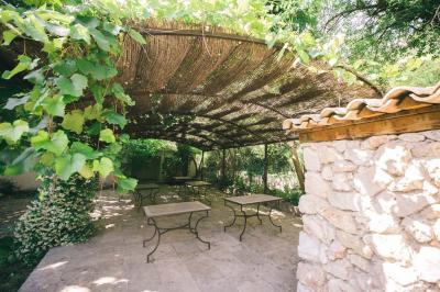 Cour intérieure pavée entourée de murs en pierre, avec des plantes grimpantes et des fenêtres sur une façade.