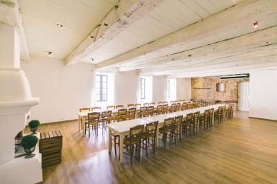 Cour intérieure pavée entourée de murs en pierre, avec des plantes grimpantes et des fenêtres sur une façade.
