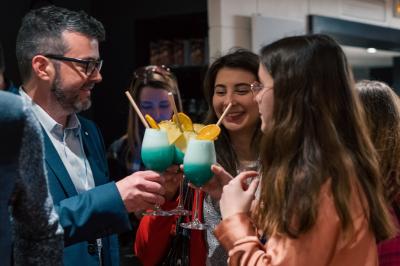 Des personnes trinquent avec des cocktails colorés dans un cadre convivial.