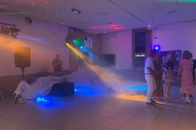 Façade d'un bâtiment en briques avec grandes fenêtres, porte ouverte et équipements audio installés à l'extérieur.