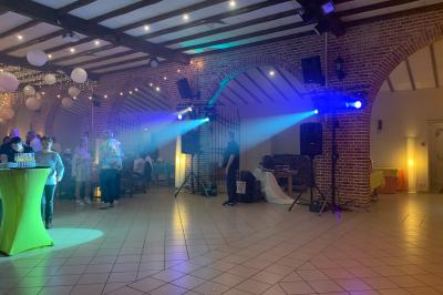 Façade d'un bâtiment en briques avec grandes fenêtres, porte ouverte et équipements audio installés à l'extérieur.