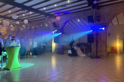 Façade d'un bâtiment en briques avec grandes fenêtres, porte ouverte et équipements audio installés à l'extérieur.