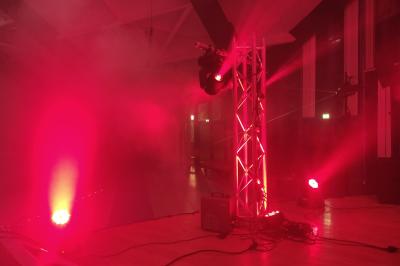 Façade d'un bâtiment en briques avec grandes fenêtres, porte ouverte et équipements audio installés à l'extérieur.