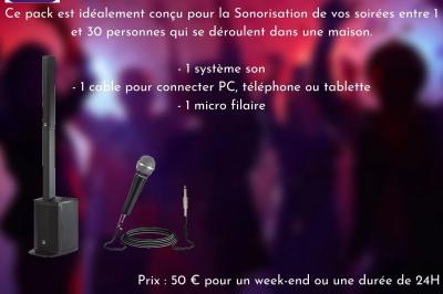 Façade d'un bâtiment en briques avec grandes fenêtres, porte ouverte et équipements audio installés à l'extérieur.