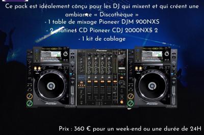 Façade d'un bâtiment en briques avec grandes fenêtres, porte ouverte et équipements audio installés à l'extérieur.