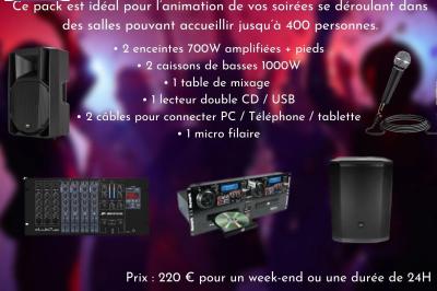 Façade d'un bâtiment en briques avec grandes fenêtres, porte ouverte et équipements audio installés à l'extérieur.