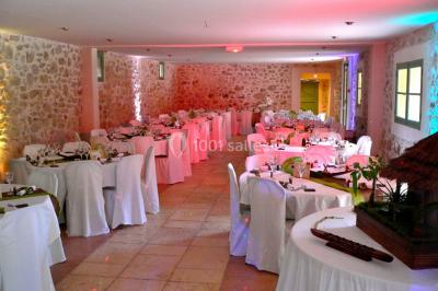 Un homme en costume parle devant une arche décorée de fleurs séchées, dans un cadre naturel avec des montagnes et des arbres.