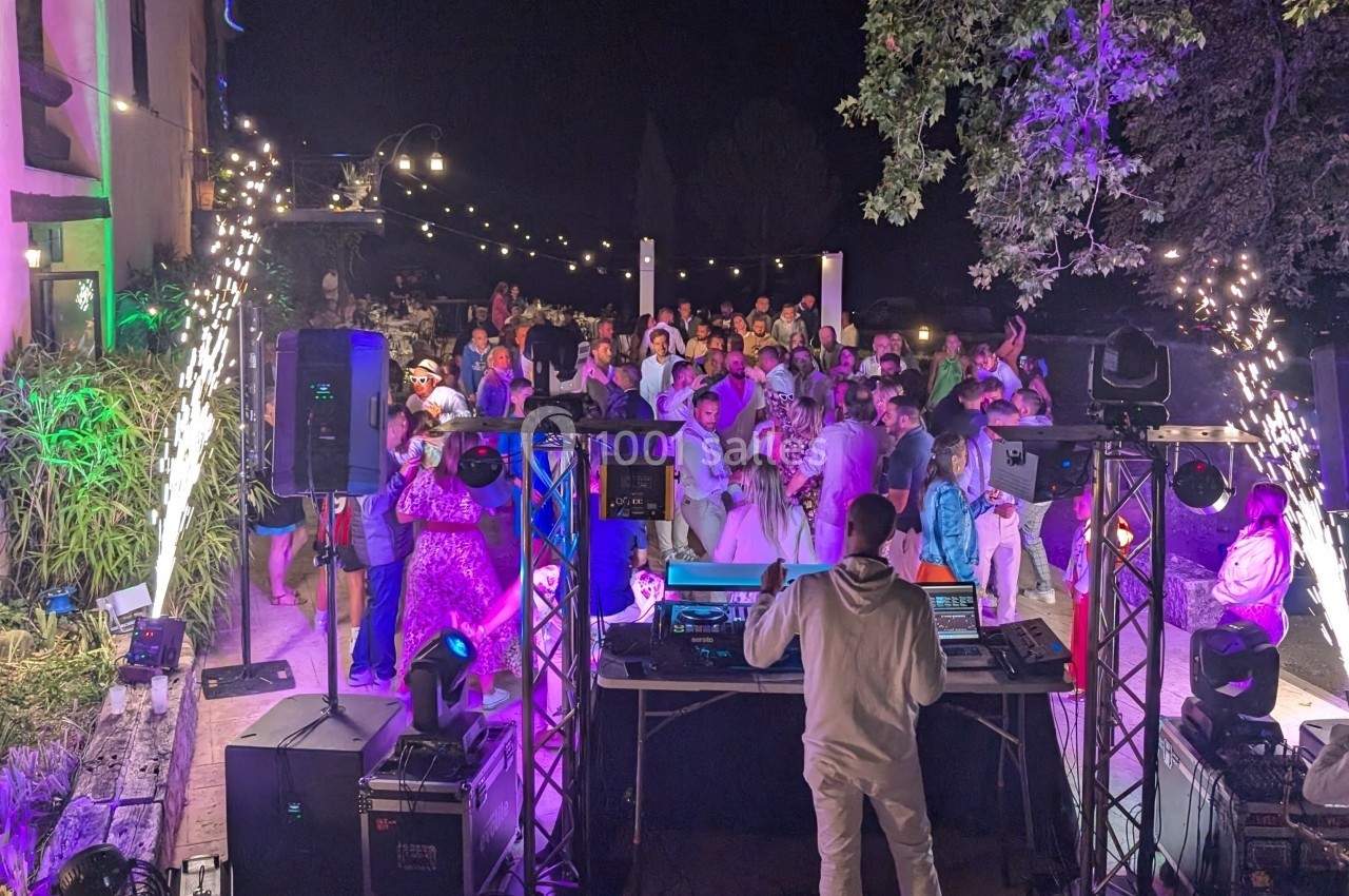 Groupe de personnes dansant en soirée en plein air, éclairée par des lumières colorées et des étincelles.