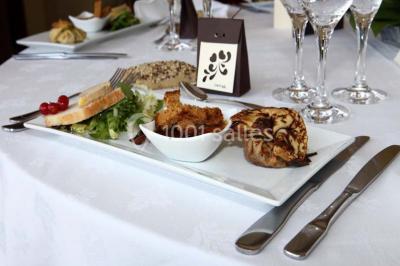 Gâteau de mariage à trois étages décoré de fleurs blanches, feuillages et roses crème au sommet.