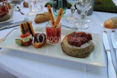 Gâteau de mariage à trois étages décoré de fleurs blanches, feuillages et roses crème au sommet.