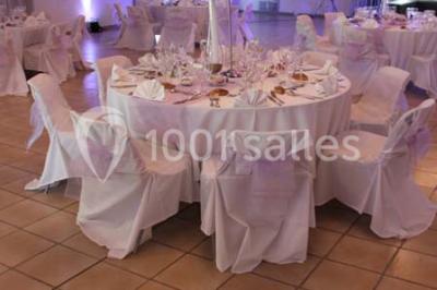 Gâteau de mariage à trois étages décoré de fleurs blanches, feuillages et roses crème au sommet.