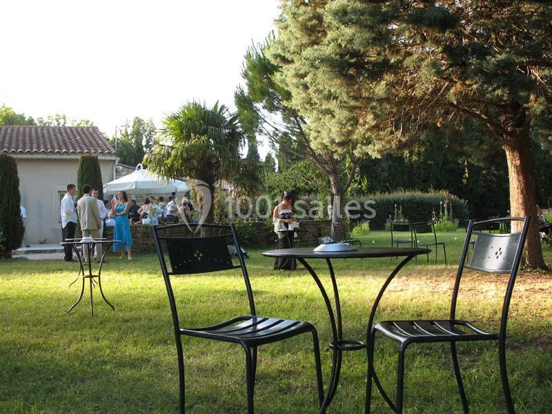 Chaises et tables en métal noir disposées sur une pelouse, avec des invités rassemblés près d'une maison en arrière-plan.