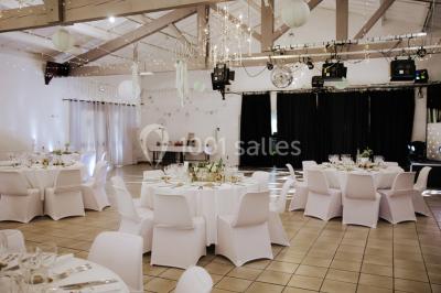 Gâteau de mariage à trois étages décoré de fleurs blanches, feuillages et roses crème au sommet.