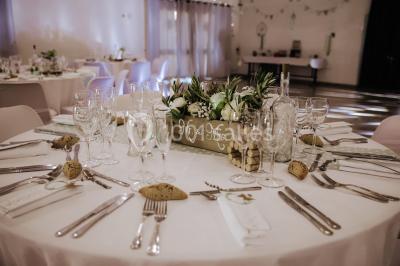 Gâteau de mariage à trois étages décoré de fleurs blanches, feuillages et roses crème au sommet.