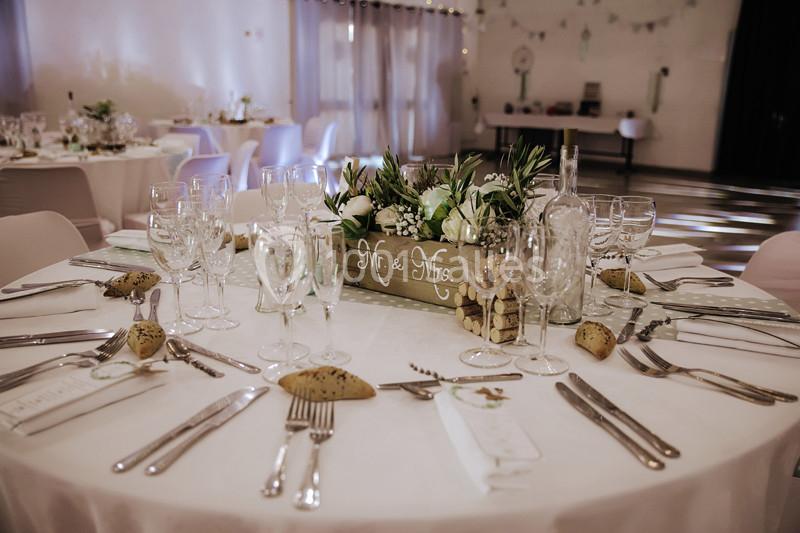 Table de réception décorée avec des fleurs blanches, des verres, des couverts et un centre de table ’Mr. & Mrs.’.
