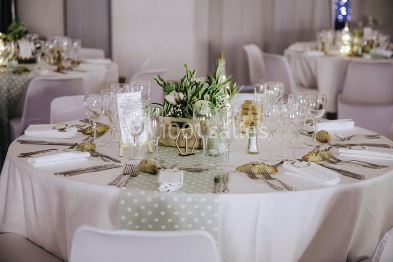 Table ronde élégamment dressée avec nappes blanches, décoration florale et vaisselle raffinée dans une salle de réception.