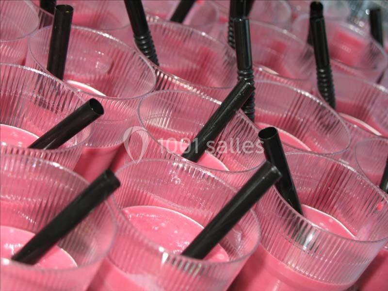 Gobelets transparents remplis de smoothie rose avec des pailles noires.