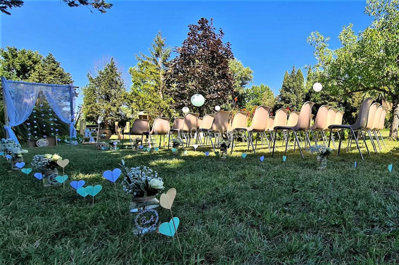 Chaises disposées en extérieur pour une cérémonie, avec une arche décorée et des fleurs sur une pelouse verdoyante.