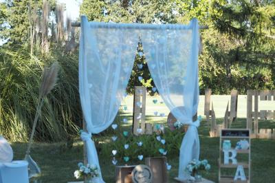 Gâteau de mariage à trois étages décoré de fleurs blanches, feuillages et roses crème au sommet.