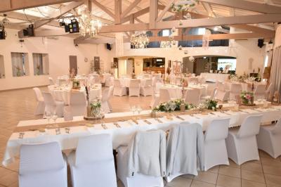Gâteau de mariage à trois étages décoré de fleurs blanches, feuillages et roses crème au sommet.