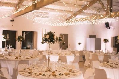 Gâteau de mariage à trois étages décoré de fleurs blanches, feuillages et roses crème au sommet.