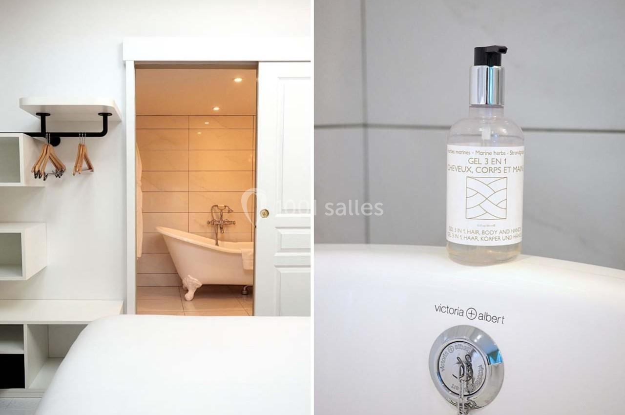 Vue d'une salle de bain avec baignoire sur pieds et détail d'un flacon de gel douche posé sur le rebord.