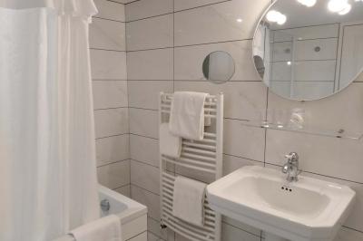 Lit avec oreillers blancs, lampe de chevet allumée et miroir reflétant une penderie et des portes dans une chambre lumineuse.