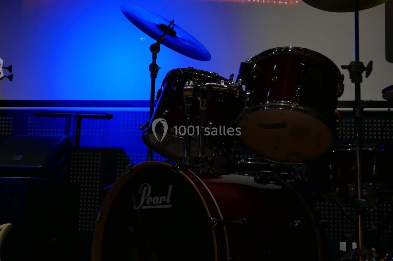 Batterie rouge installée sur une scène faiblement éclairée avec un fond bleu lumineux.