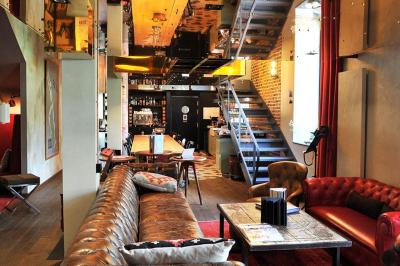 Lit avec oreillers blancs, lampe de chevet allumée et miroir reflétant une penderie et des portes dans une chambre lumineuse.